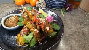 A delicious serving of satay chicken skewers with extra satay sauce, quickly, Asian slaw and a lime wedge