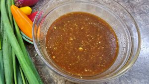 The finished Nam Jim Jaew Thai dressing in a glass bowl, showcasing a rich dark brown colour and glossy consistency.
