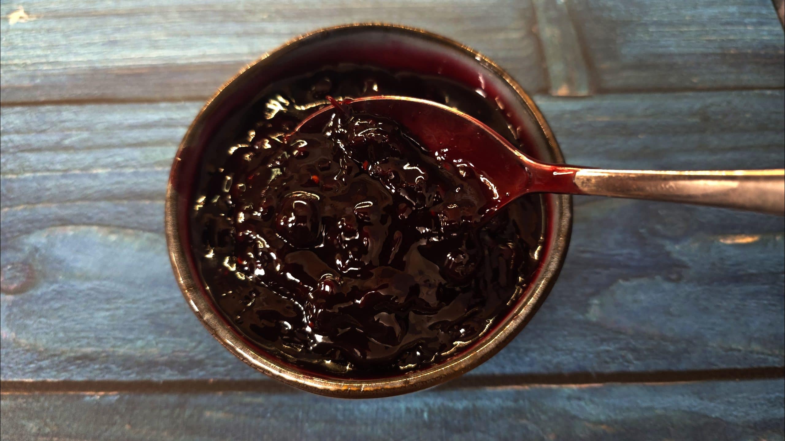 Overhead close-up of a spoonful of thick berry compote showing the rich colour and fruit texture.